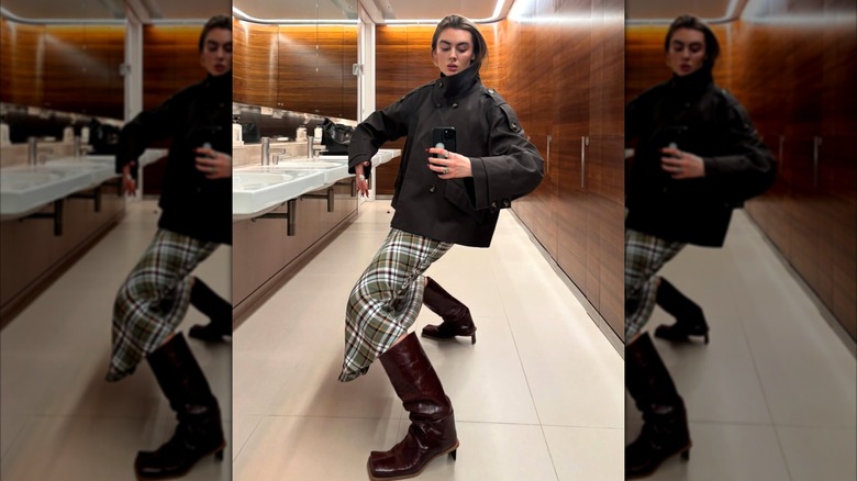 A woman in a brown plaid skirt and square toed boots