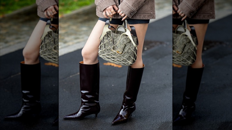 A woman in black vinyl boots with a short skirt