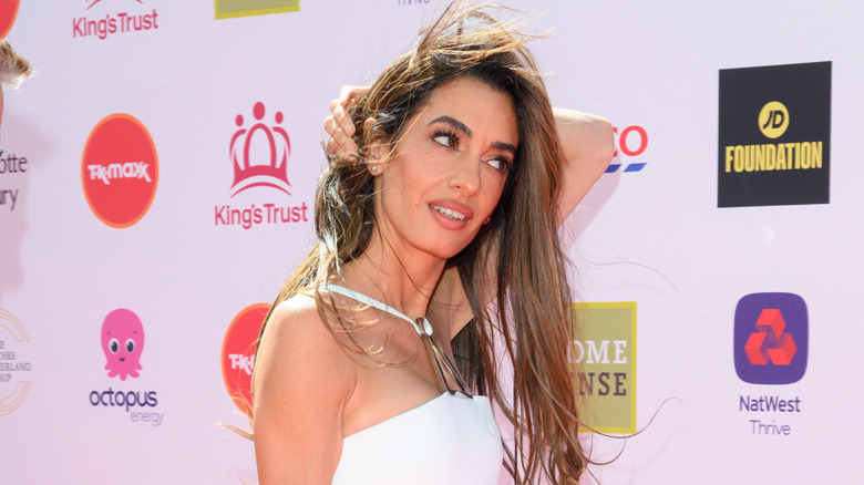 Amal Clooney looks to the right in white dress
