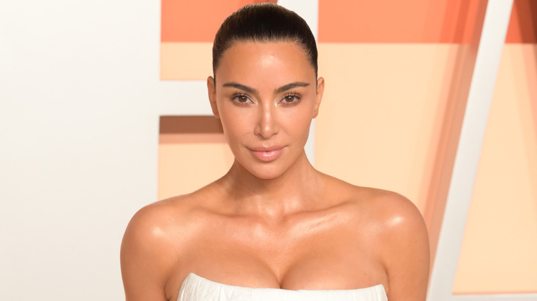 Kim Kardashian smiles wearing white sleeveless dress