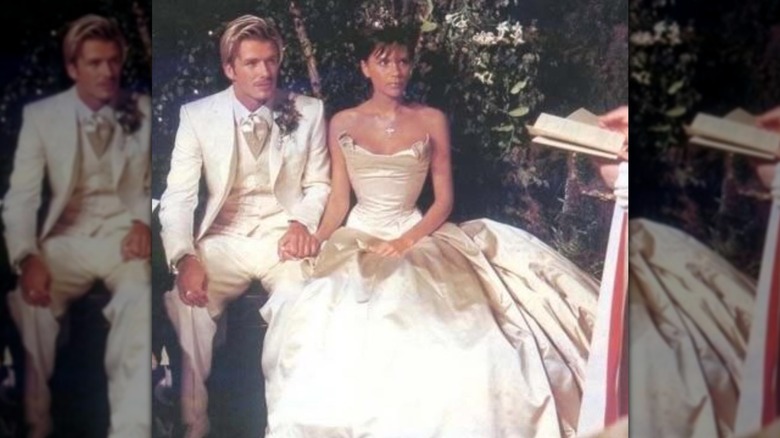 Victoria Beckham sits next to David Beckham wearing satin wedding dress