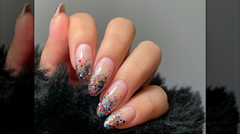 A woman's hand showing a manicure using multi-colored, chunky glitter