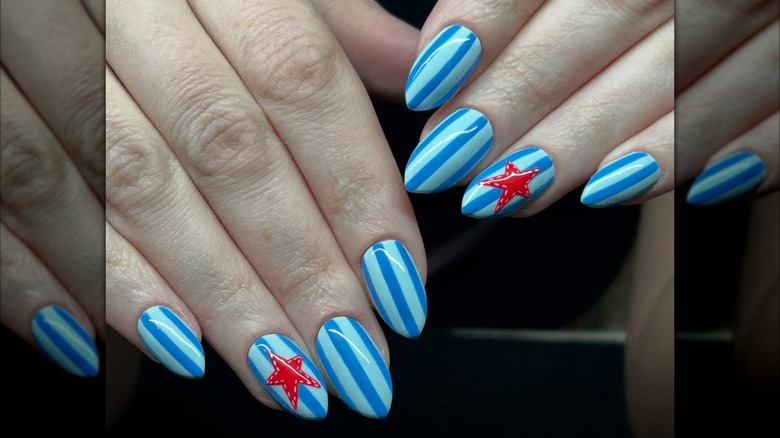 Two hands showing a blue striped manicure with a red star