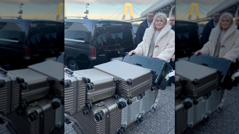 Martha Stewart rolling a cart with seven silver suitcases