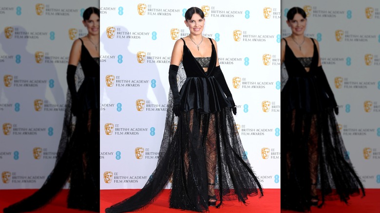 Millie Bobby Brown in a black lacy dress and black gloves