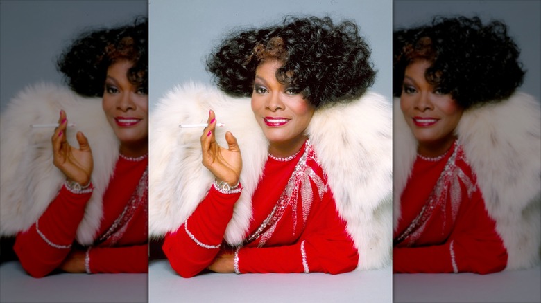 Dionne Warwick smiles wearing a fur shrug and a red top