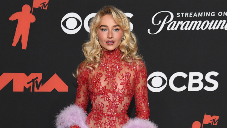 Sabrina Carpenter in a red dress and pink boa on the red carpet