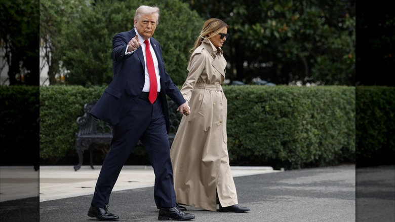 Melania and Donald Trump holding hands leaving the White House with her in a trench coat