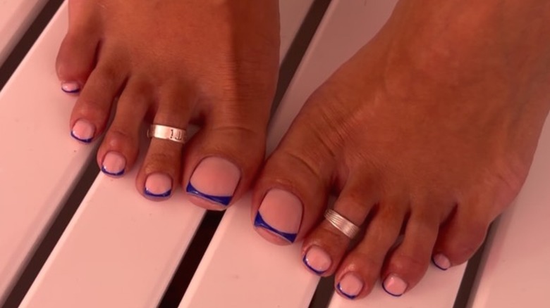 A woman's feet with a dark blue micro-French tip manicure