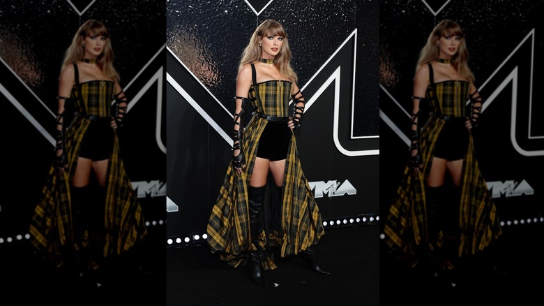 Taylor Swift poses wearing a tartan corset and skirt