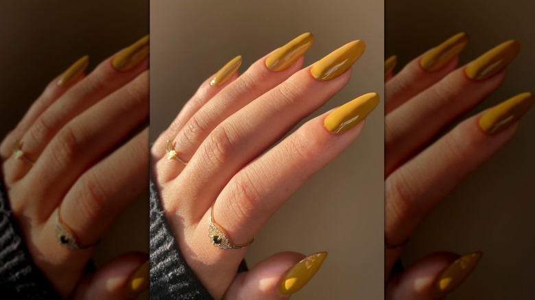 A woman with yellow nails on Instagram wearing gold rings