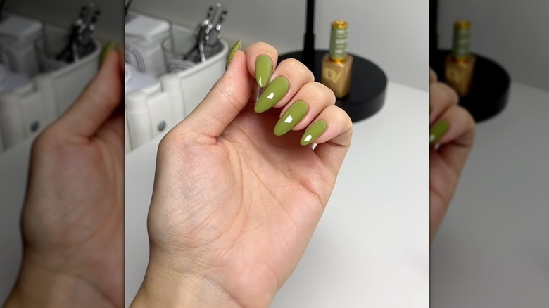 A woman holding her hand out with green nail polish