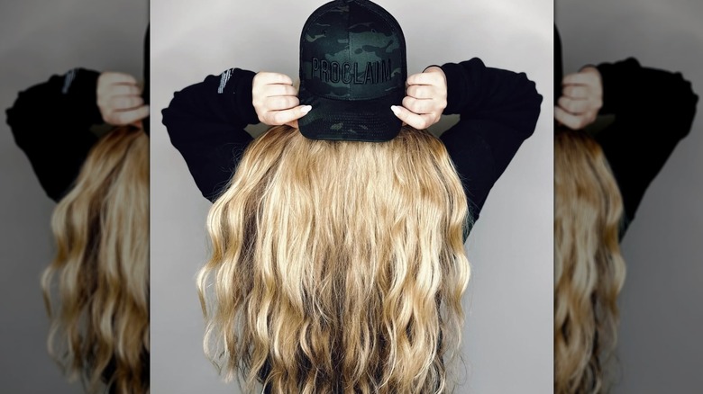 The back side of Erika Kirk's head while holding a black ball cap
