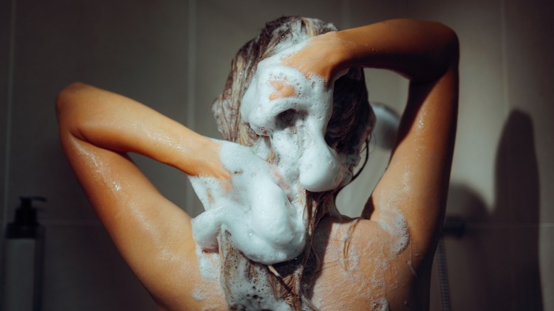 A woman applying shampoo in the shower