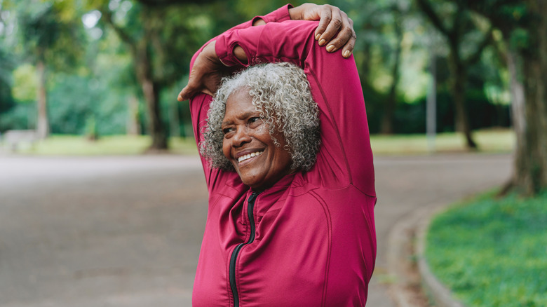 Mature woman outside smiling with her arms overhead