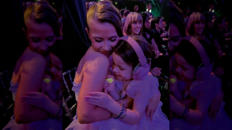 Bindi Irwin hugging her daughter grace in a dark room illuminated in purple light