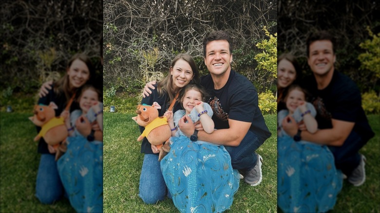 Bindi Irwin and Chandler Powell hugging their daughter Grace who is dressed in a Cinderella costume