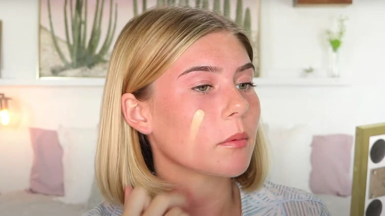 woman applying foundation on sunburn