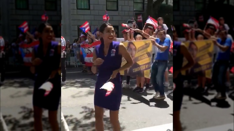 Alexandria Ocasio-Cortez at a parade in a blue sleeveless dress