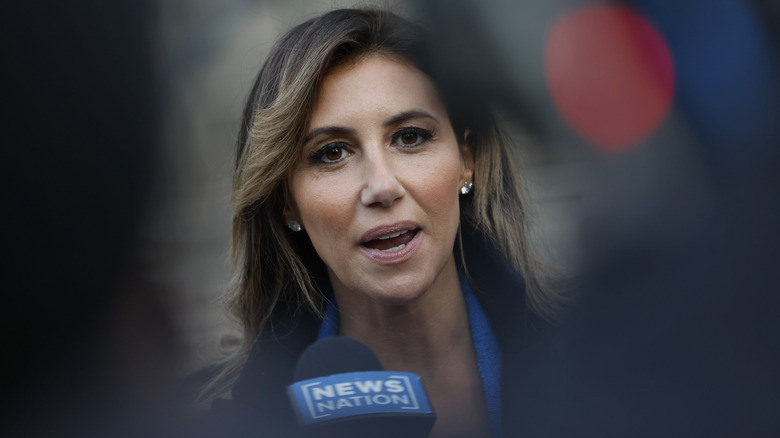 Alina Habba with diamond earrings talking into a "News Nation" microphone