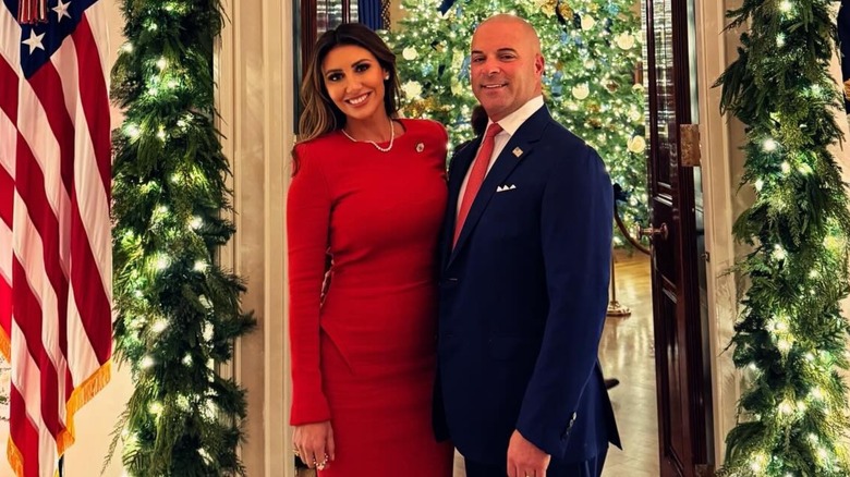 Alina Habba posing alongside her former husband Gregg Reuben in front of the White House holiday decorations