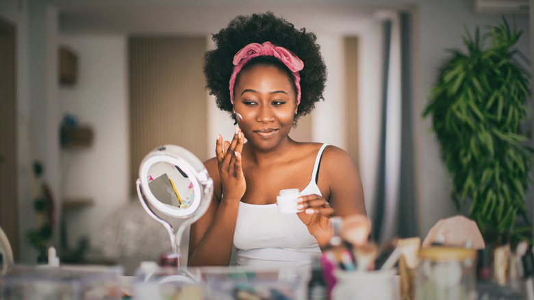 Woman applying cream to her face