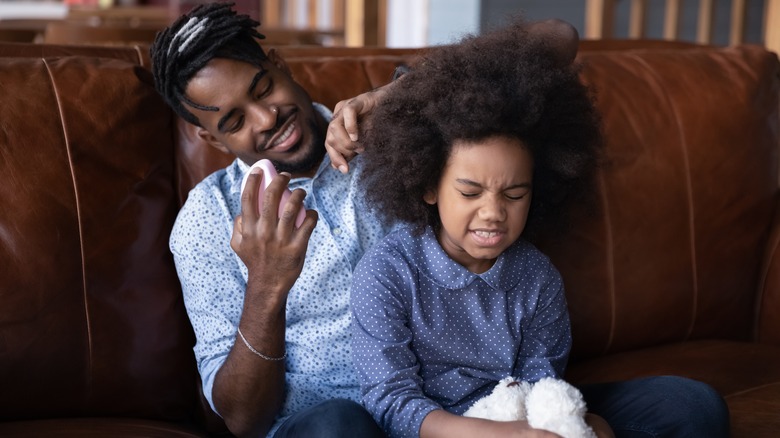 man detangling daughter's hair