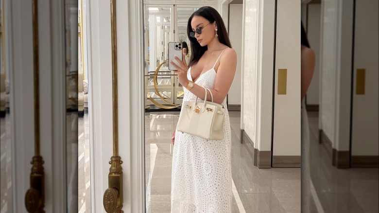 Woman wearing a white dress and cream bag