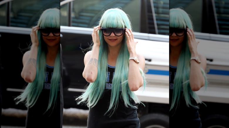 Amanda Bynes walks wearing a turquoise wig and large sunglasses