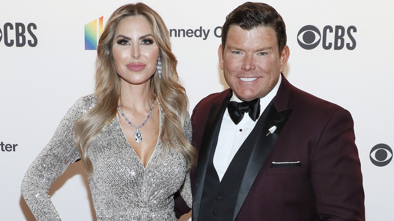 Amy Baier in a silver dress standing next to Bret Baier on the red carpet