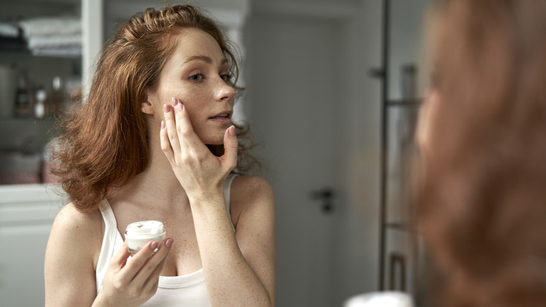 Woman applying skincare in the mirror