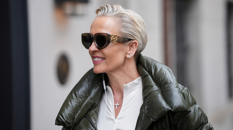 A stylish older woman with oversized sunglasses and short hair