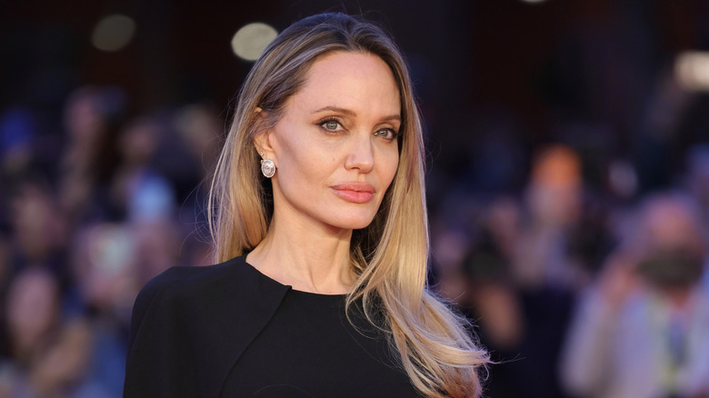 Angelina Jolie in a black dress with long blonde hair at an event