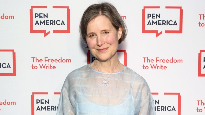 Author Ann Patchett smiling in a light blue dress in front of a white background