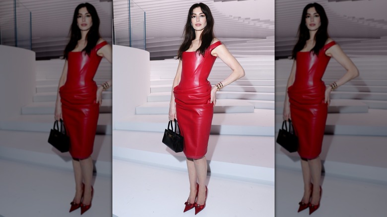 Anne Hathaway posing in a read leather dress at Milan Fashion Week in 2024