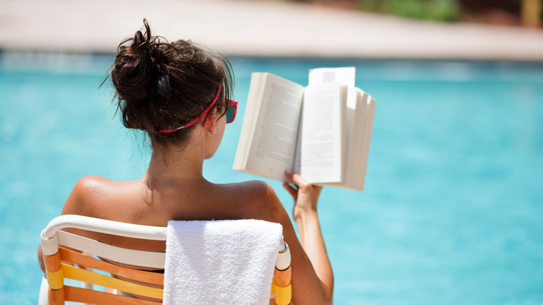 Woman reading book by the pool