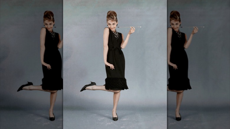 Audrey Hepburn posing for a promo photo for Breakfast at Tiffany's, wearing a black knee-length dress and black heels