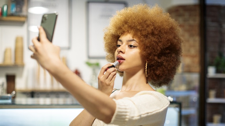 A woman applying lipstick