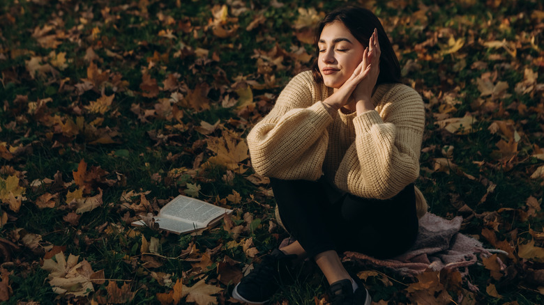 A woman reading outdoors in the fall