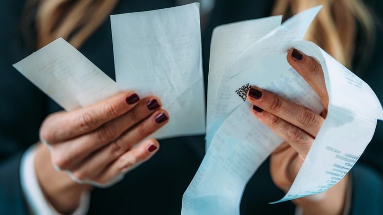 Hands holding six receipts