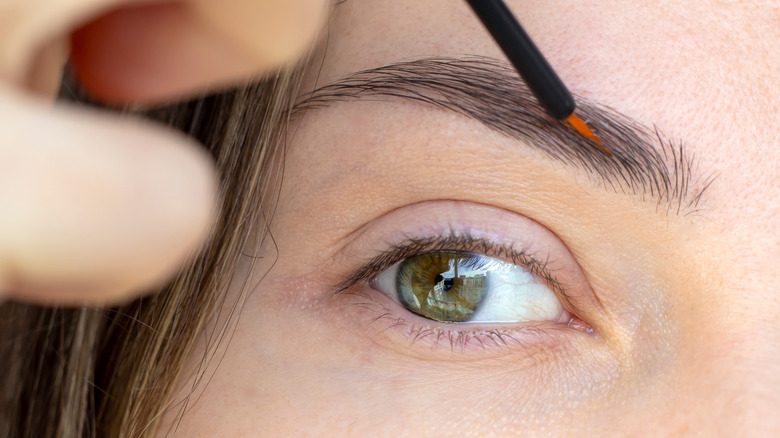 Woman applying product to eyebrows