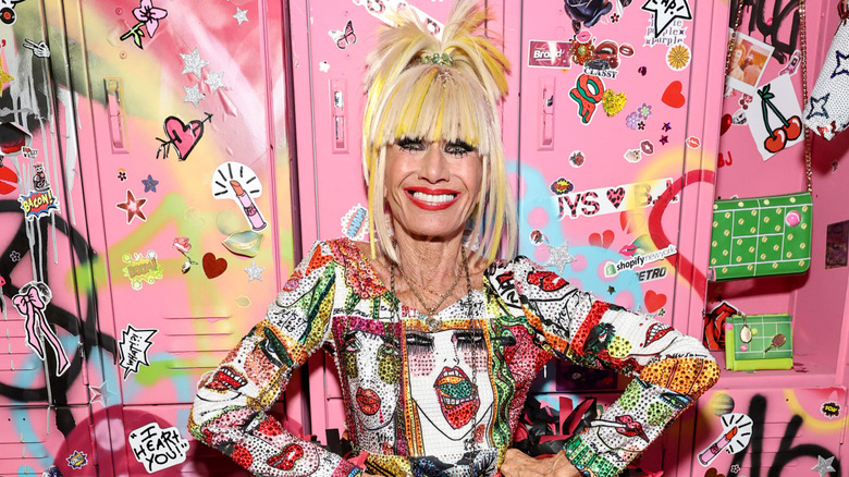 Betsey Johnson with her hair half up in a big ponytail in a brightly colored dress