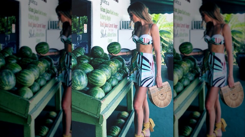 Bettina Anderson in a bralette top and skirt by a watermelon stand