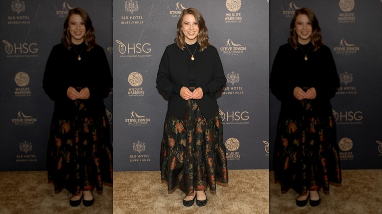 Bindi Irwin on the red carpet in a black jacket and floor-length floral skirt
