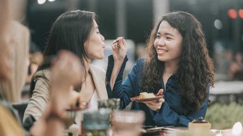 One girl feeds another girl a plate of food