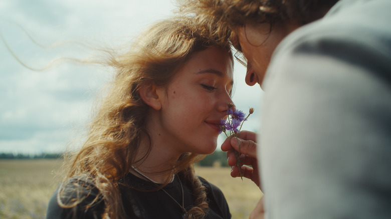 A girl with curly hair smells purple flowers
