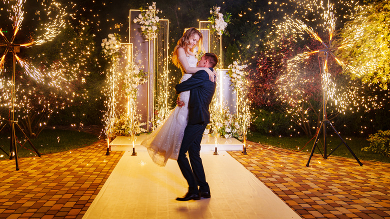 A bride and groom cutting embracing in front of spinning fireworks