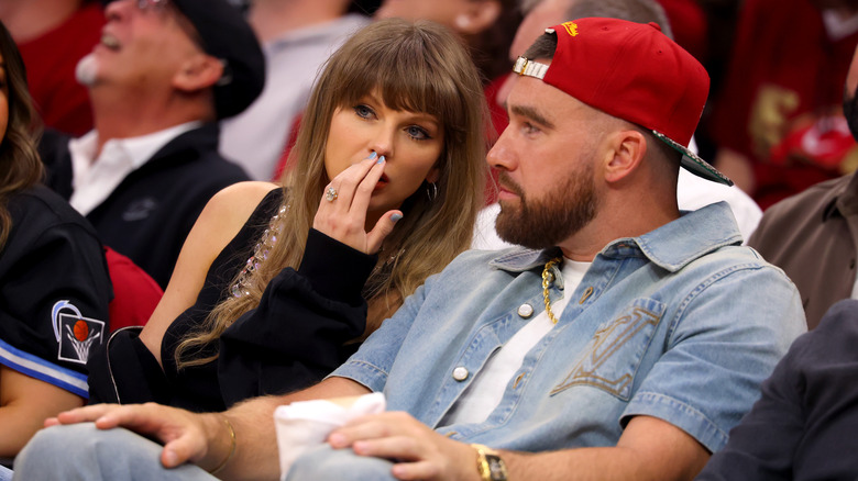 Taylor Swift and Travis Kelce sitting court-side at a basketball game