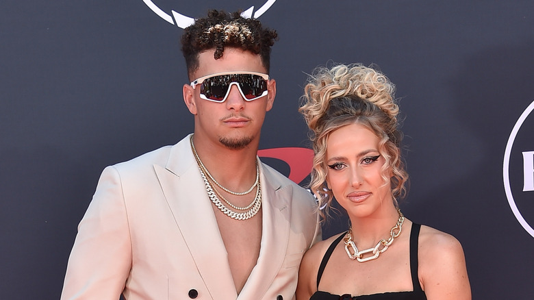 Patrick Mahomes in sunglasses alongside Brittany Mahomes in a sleeveless black dress