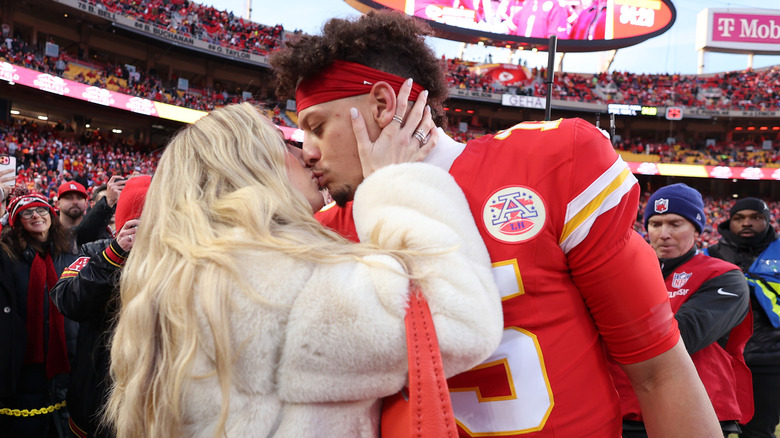 Brittany Mahomes kissing Patrick Mahomes on the football field